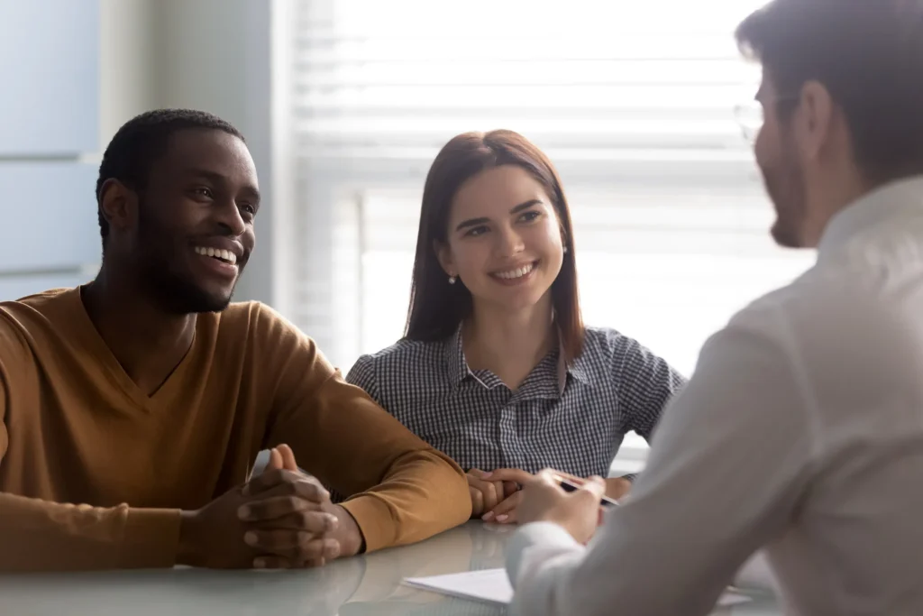 A smiling couple speaking with an attorney.